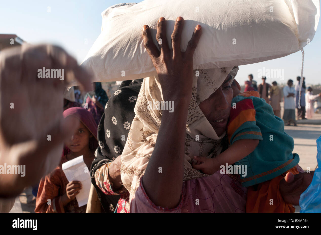 Pakistan Sindh Provinz Shaddat Kot. Nach der Flut. Dezember 2010. Eine Frau trägt nach Hause ihren Mehlsack Weizen. Stockfoto
