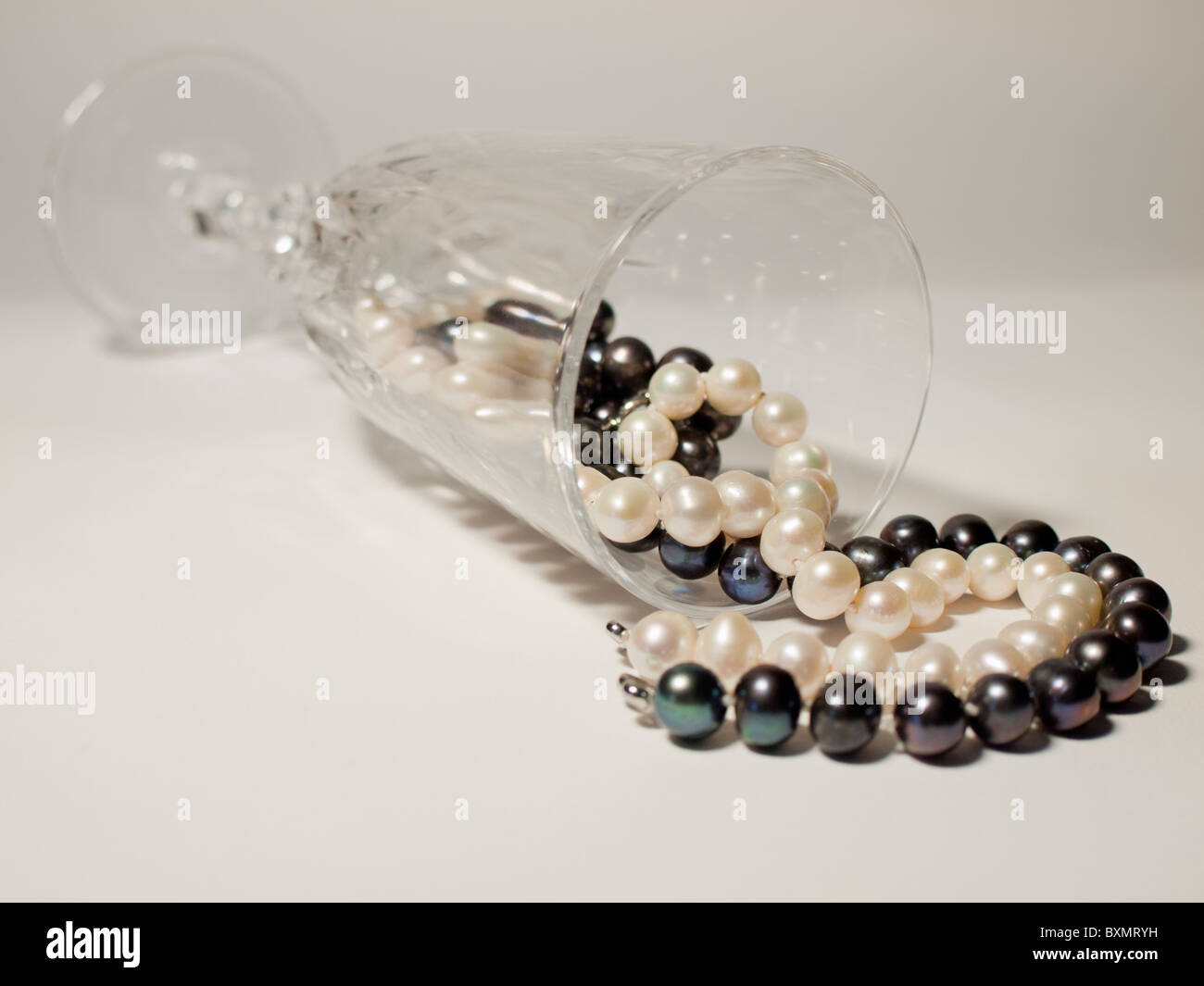 schwarze und weiße Perlenkette innen verlegen Sektglas Stockfoto