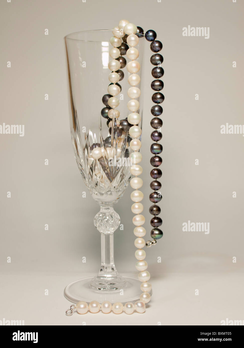 schwarze und weiße Perlenkette im Inneren stehen Champagner Glas Stockfoto