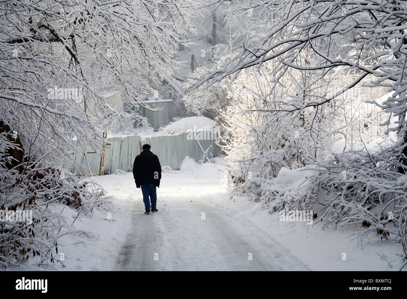 Ein Mann geht auf einer verschneiten Straße in Germia Park, einem öffentlichen Bereich außerhalb Prishtina im Kosovo. Stockfoto