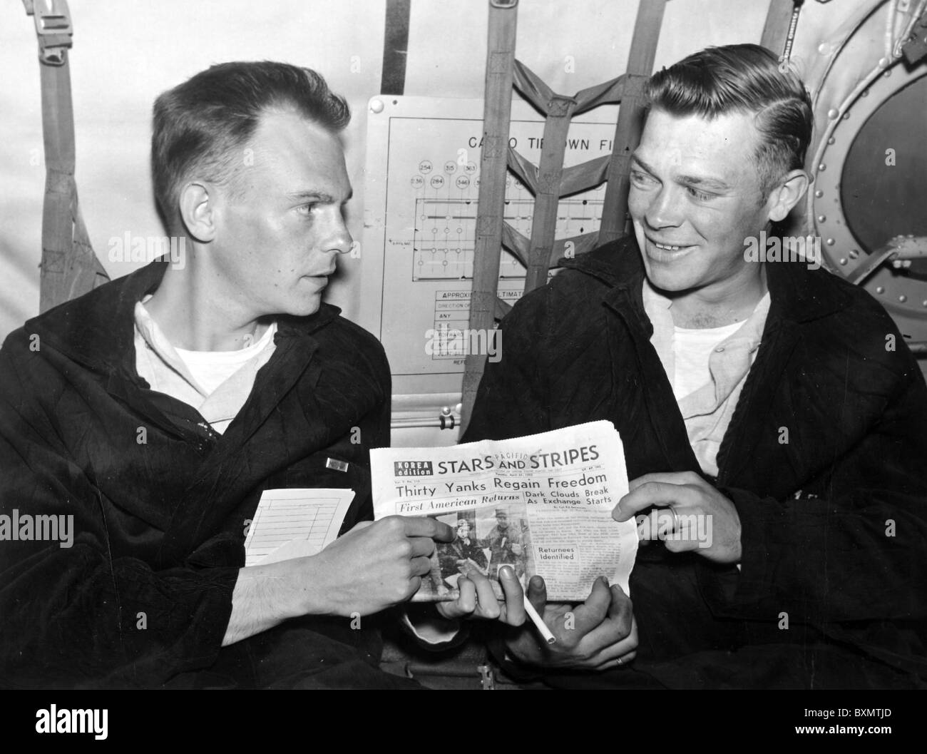 Bekämpfung Fracht auf dem Weg nach Japan---1st Lt. Roy M. Jones (links) und Sgt. Gerald Neighbors blickt auf eine Seoul Edition von Sternen Stockfoto