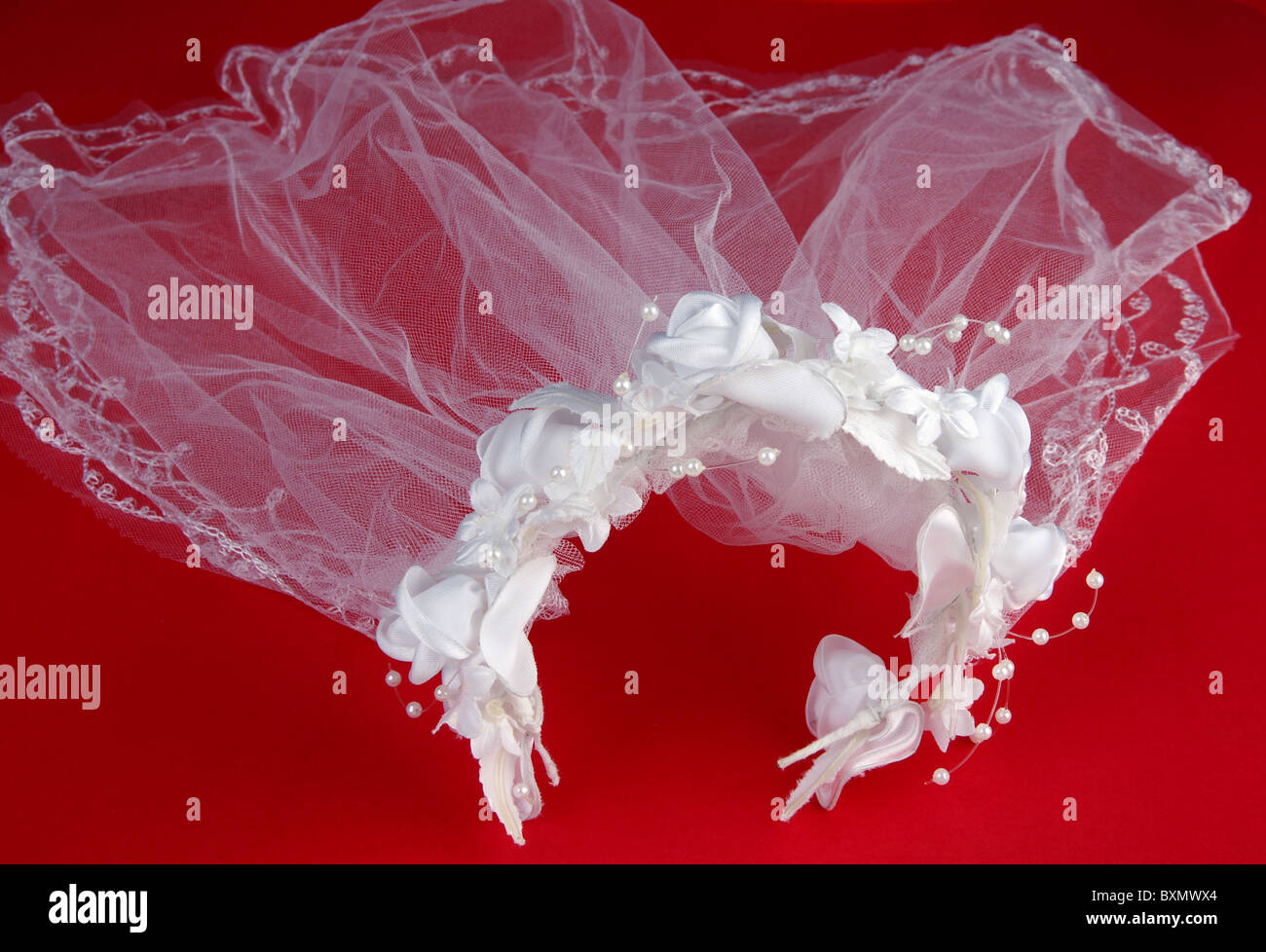 weiße Hochzeitsschleier mit Kopfschmuck. Auf rotem Hintergrund Stockfoto