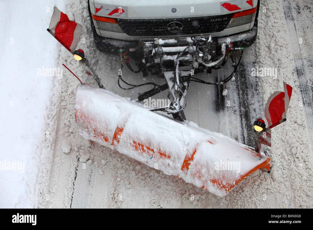 Winter, Verkehr in einem Stadtzentrum, Schnee bedeckte Straßen. Straße und Gehweg Reinigung, Schneepflug in Aktion. Stockfoto