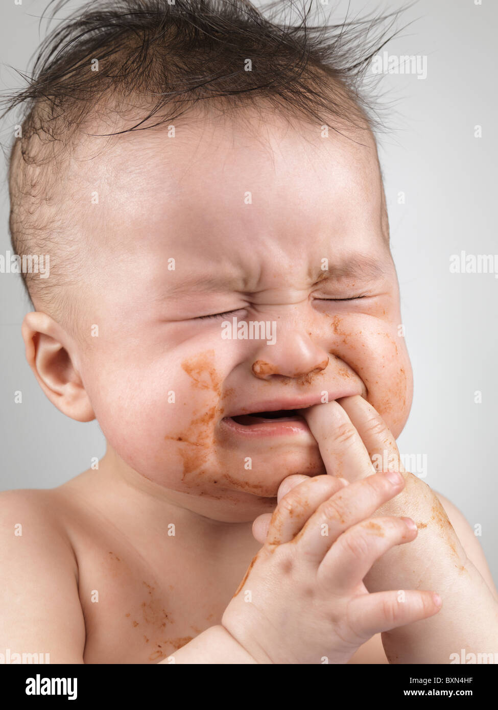 Lizenz erhältlich unter MaximImages.com - künstlerisches Porträt eines weinenden siebenmonatigen Jungen mit unordentlichen Haaren und mit Nahrungsgesicht verschmiert Stockfoto