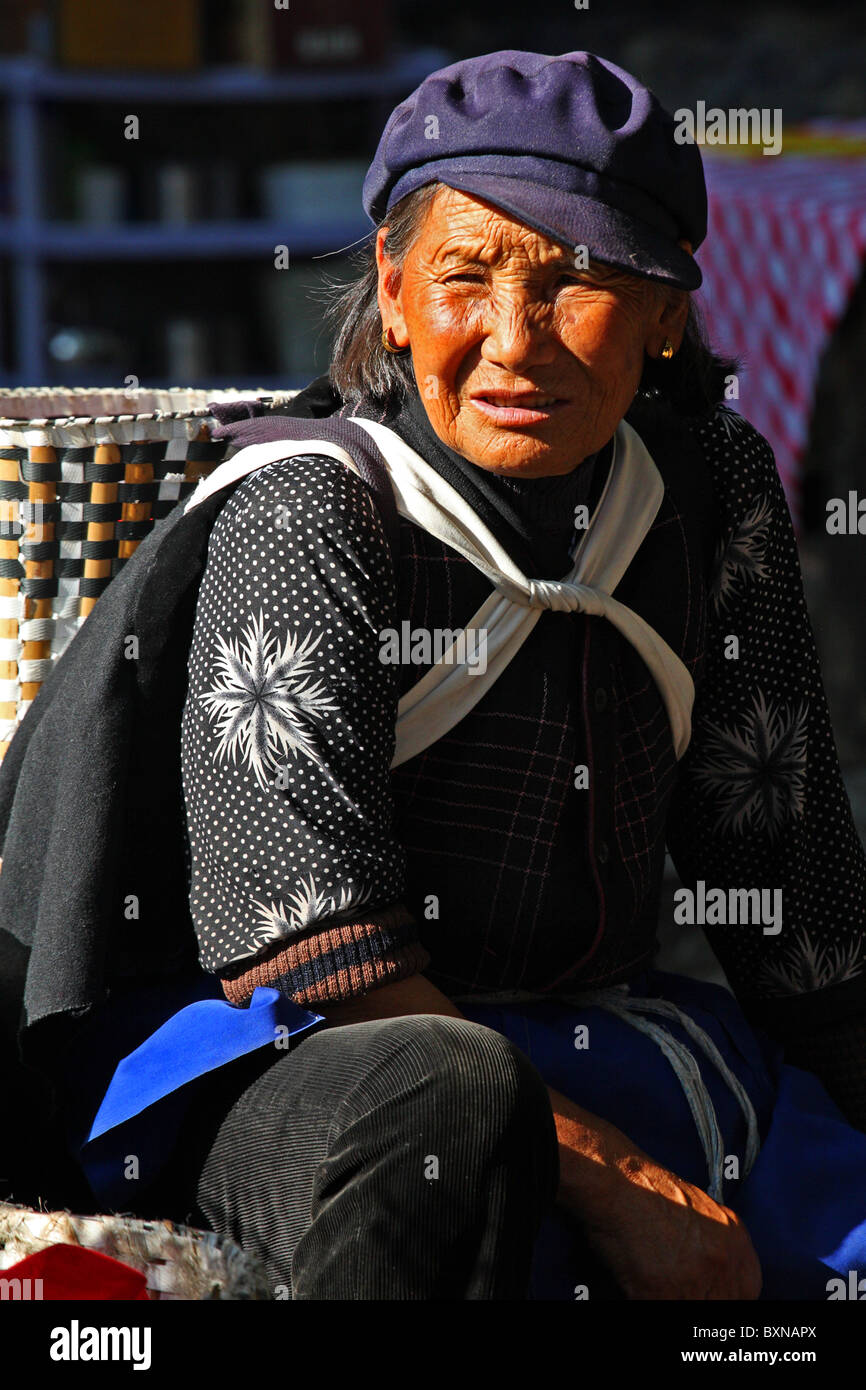 Naxi Frau sitzend auf Straße, Lijiang, Provinz Yunnan, China Stockfoto