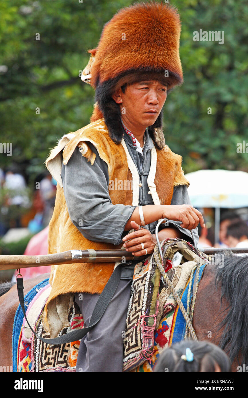 Chinesischer Mann auf dem Pferderücken verkauft Ausritte in Lijiang, China Stockfoto