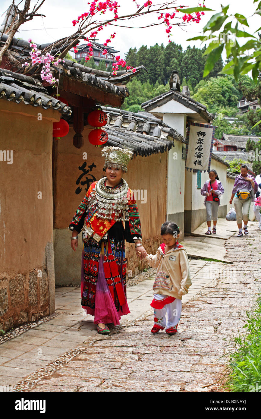 Frau in traditioneller Tracht geht mit Kind durch die Altstadt von Lijiang, Provinz Yunnan, China Stockfoto