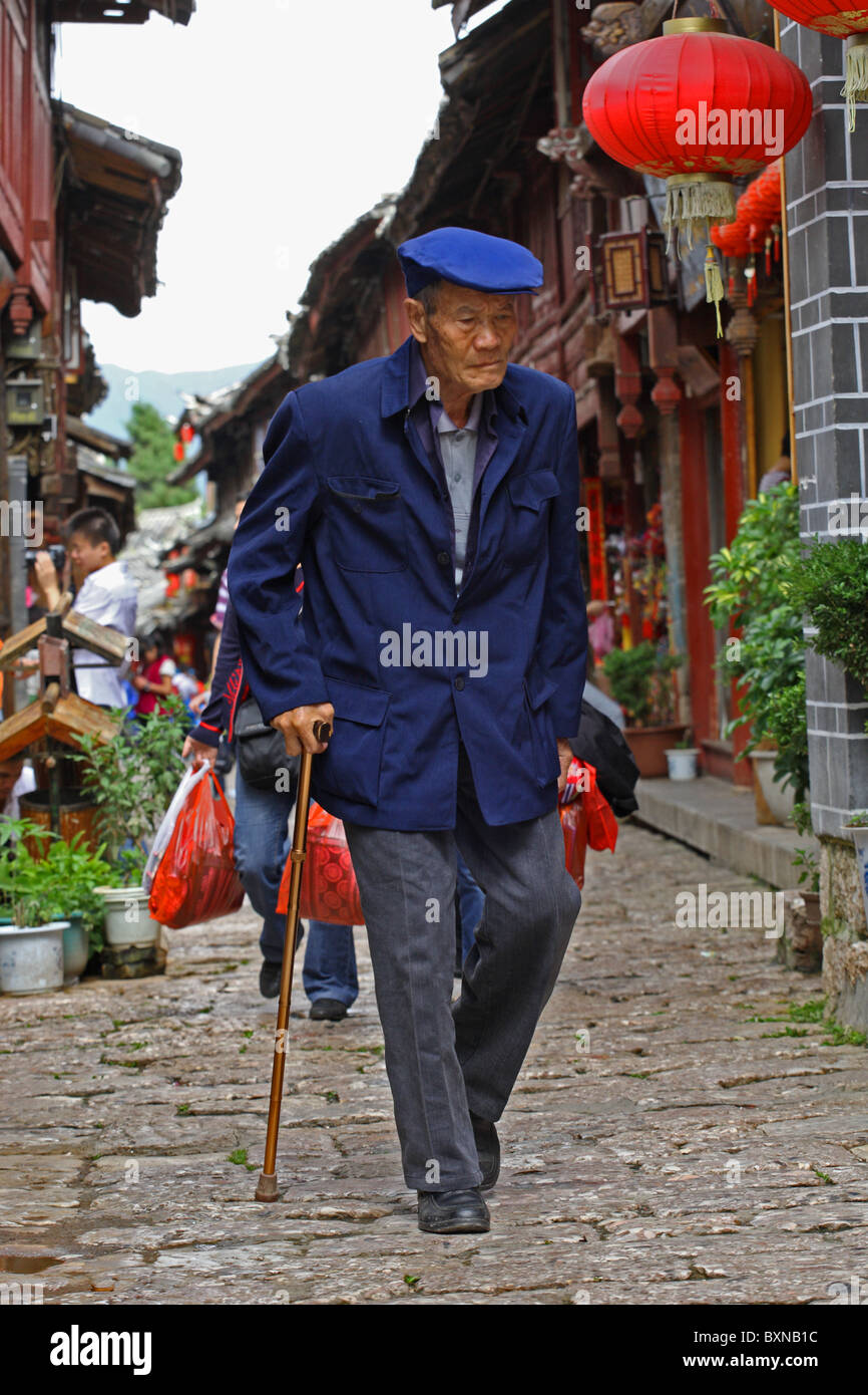 Älterer Herr, der zu Fuß gepflasterten Gassen von Lijiang, Provinz Yunnan, China Stockfoto