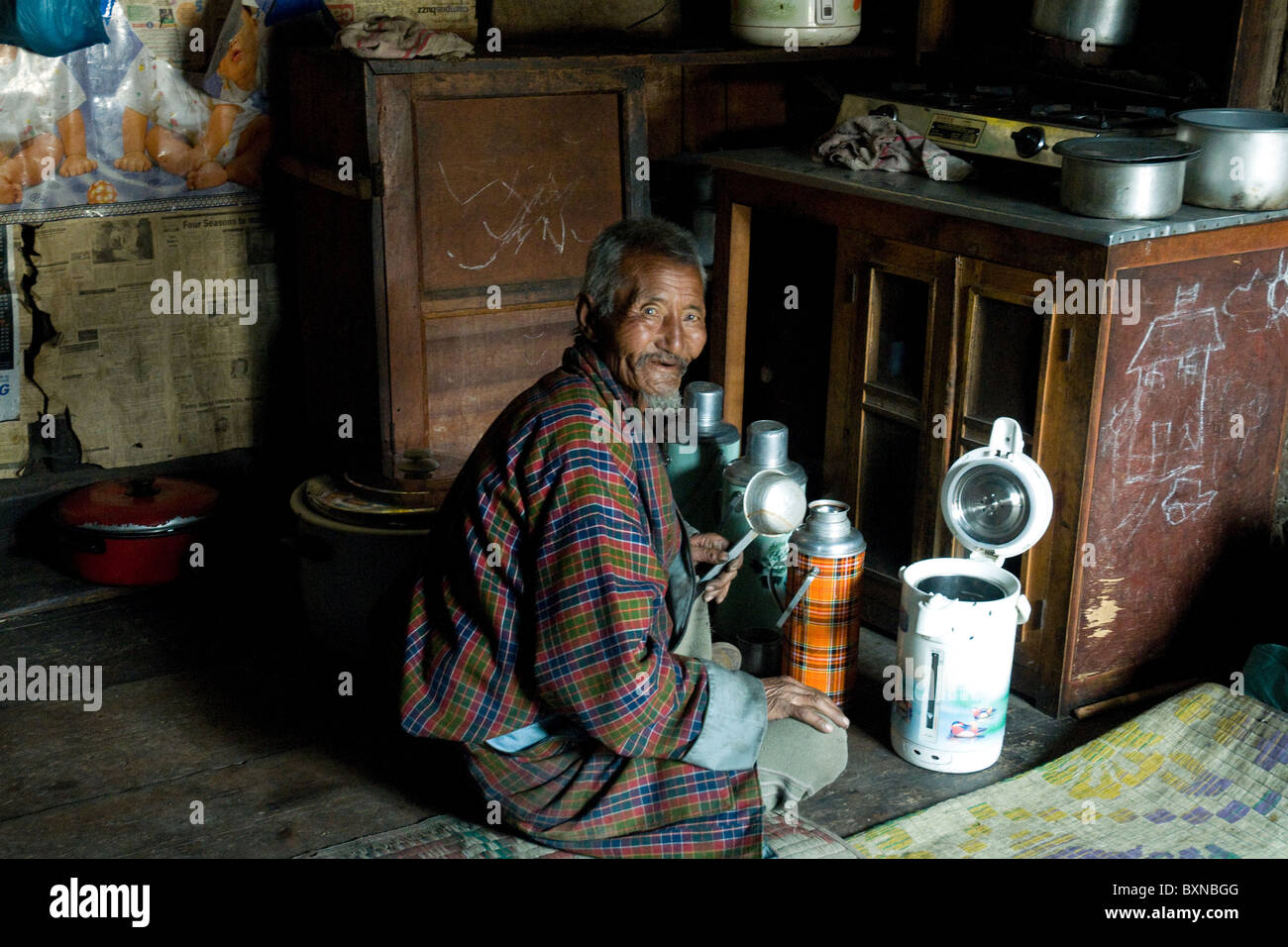 In der Küche seiner Heimat in Bhutan Bauernhaus bereitet der Familie Patriarch eine Thermoskanne mit Tee Stockfoto