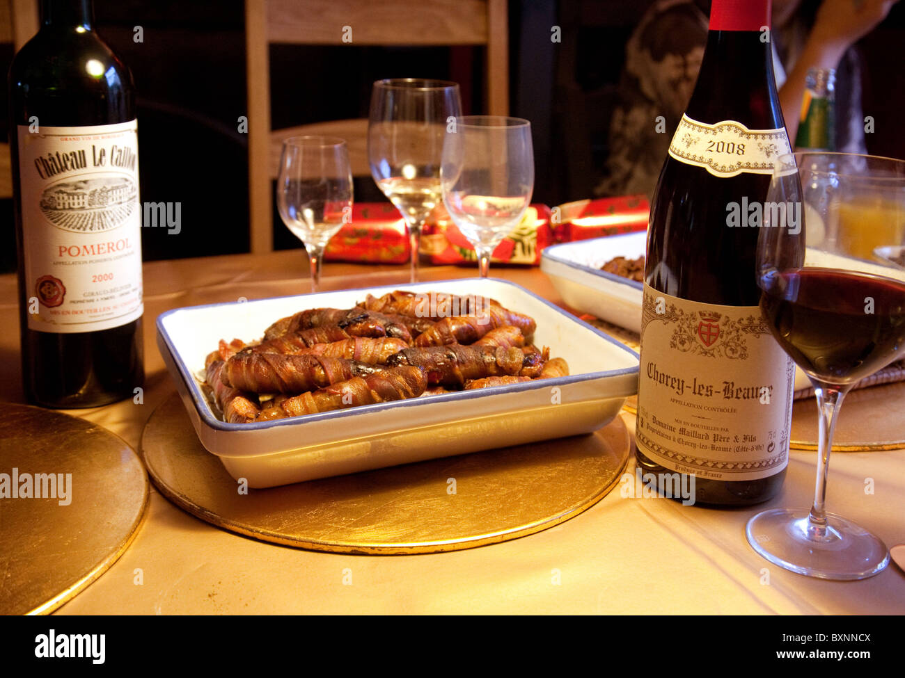 Würstchen, eingewickelt in Speck und Flaschen Rotwein auf dem Weihnachtstisch Abendessen, UK Stockfoto