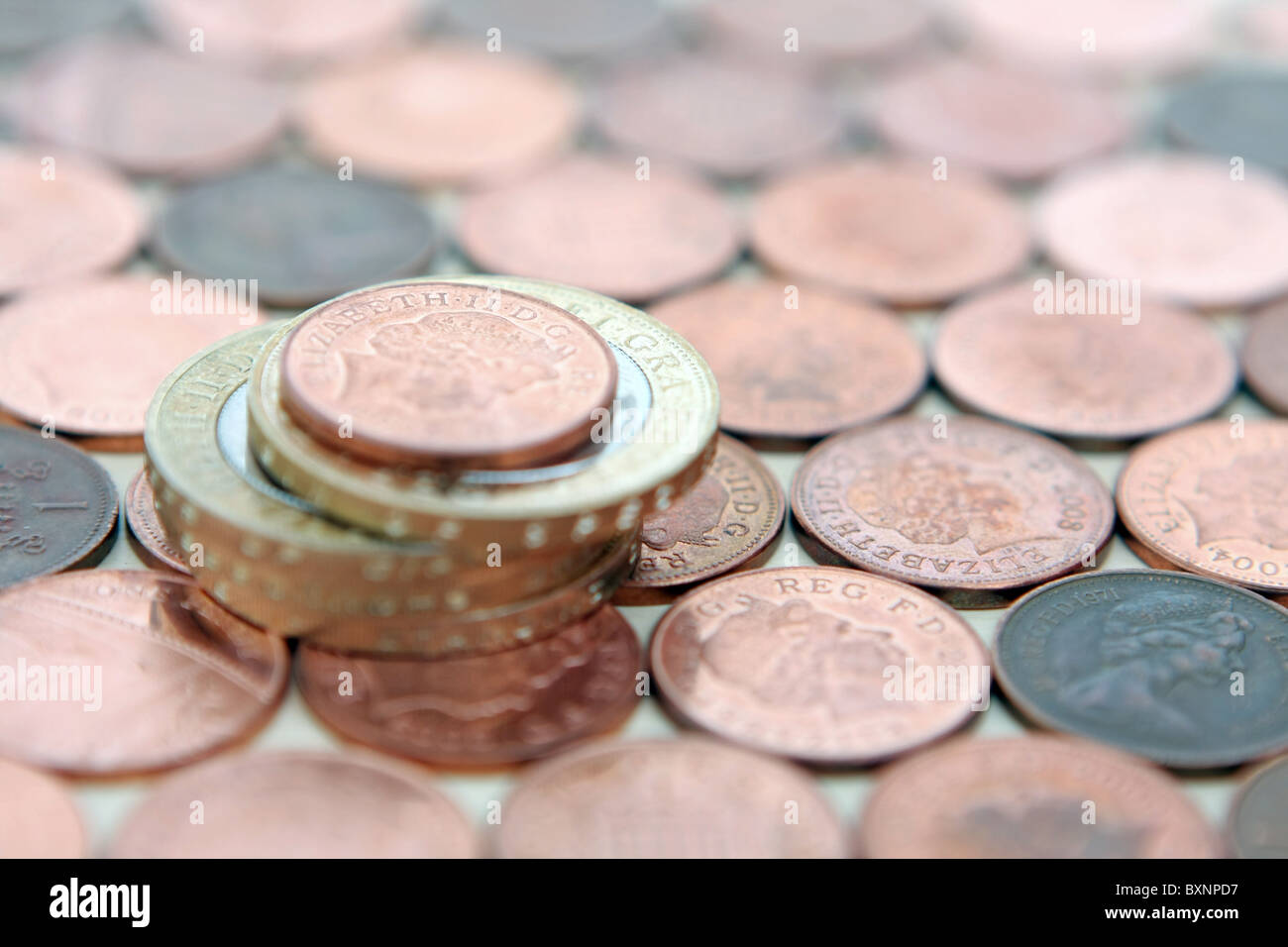 Ein Pfund Sterling 1 p Münze auf einen Stapel von £2 Münzen - alles auf einem Hintergrund von 1-p-Münzen Stockfoto