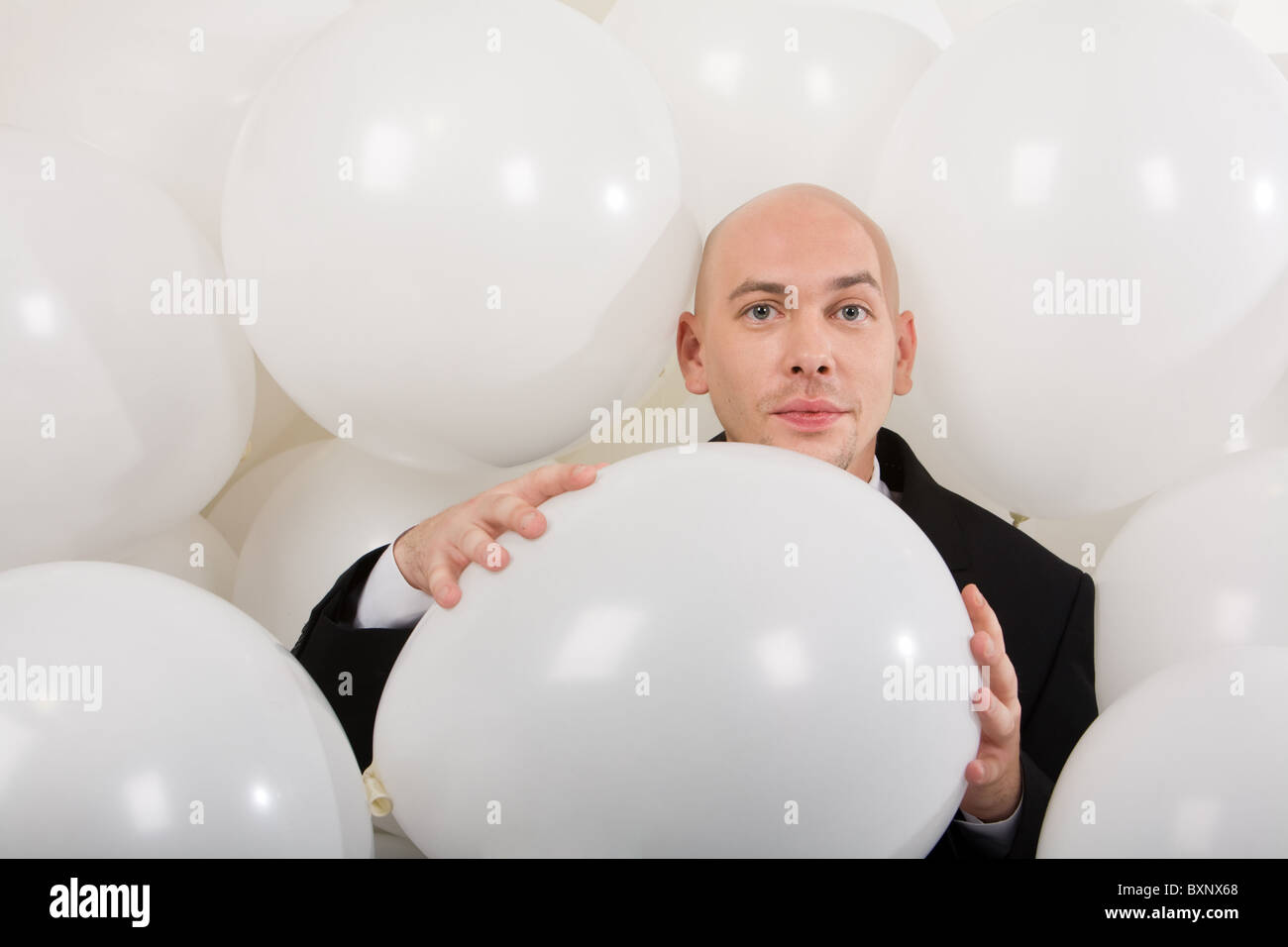 Foto von attraktiven männlichen großen weißen Ballon in den Händen halten und Blick in die Kamera Stockfoto
