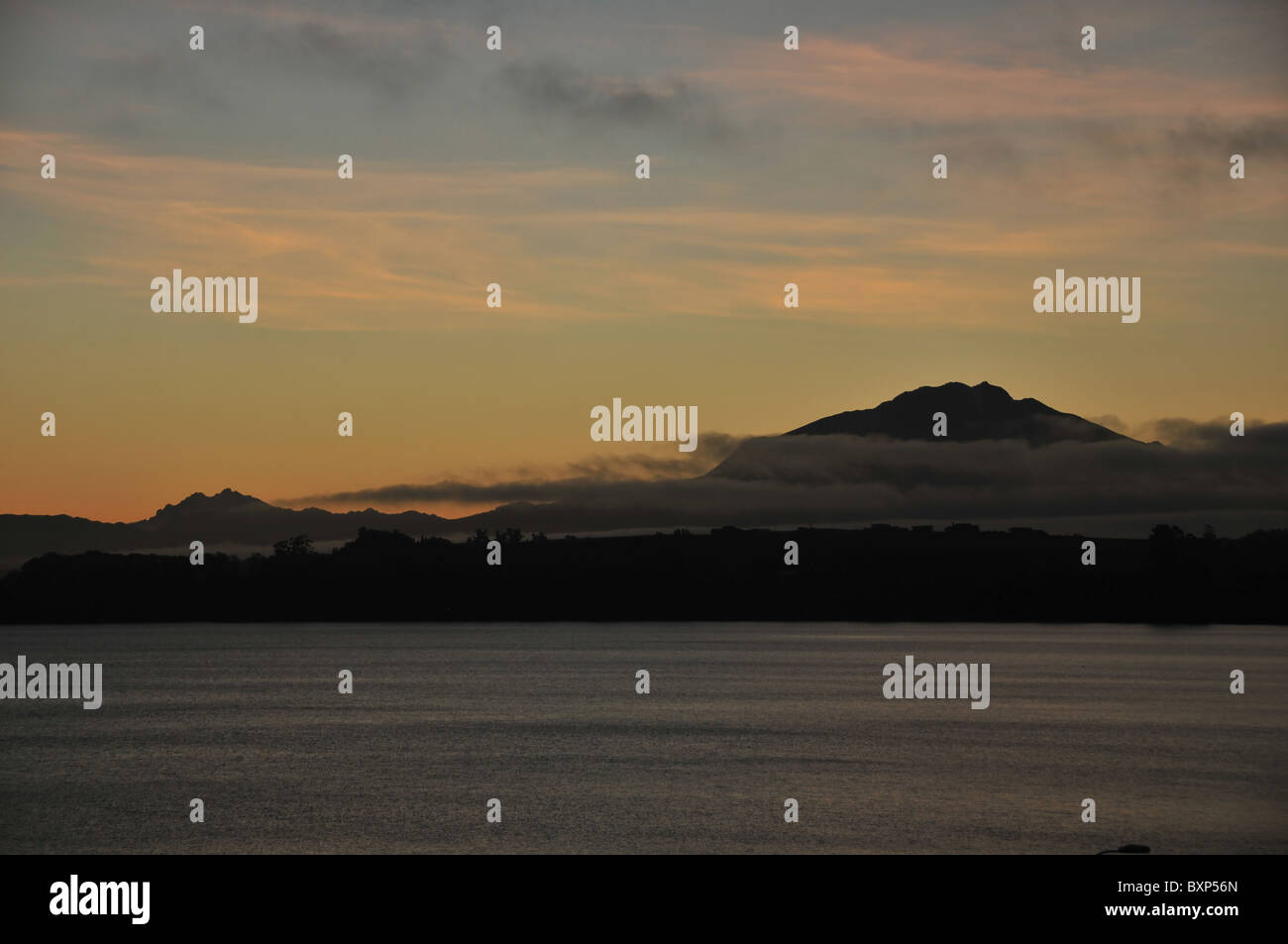 Dawn Silhouette des Volcan Calbuco, steigt durch Wolken hindurch, über das graue Meer See Llanquihue, aus Puerto Varas, Chile Stockfoto
