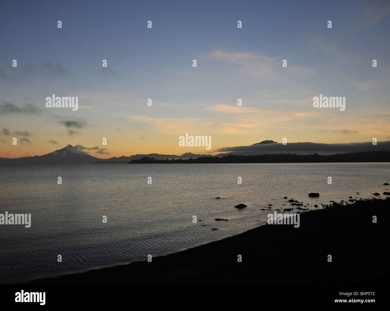 Dawn gedreht, vom Strand Puerto Varas, Osorno und Calbuco Vulkanen durch Wolken hindurch, über Wasser der See Llanquihue, Chile Stockfoto