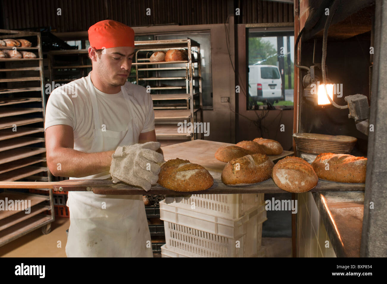 Handwerker-Sauerteig-Bäcker entfernen frisch gebackenes Brot aus einer Woodfired Ofen Stockfoto