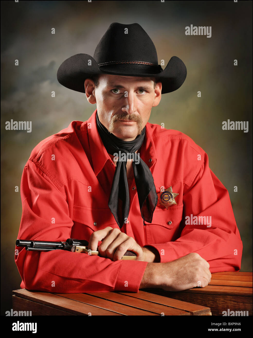 gut aussehend Western Cowboy mit Pistole und Abzeichen im Studio sitzen ...