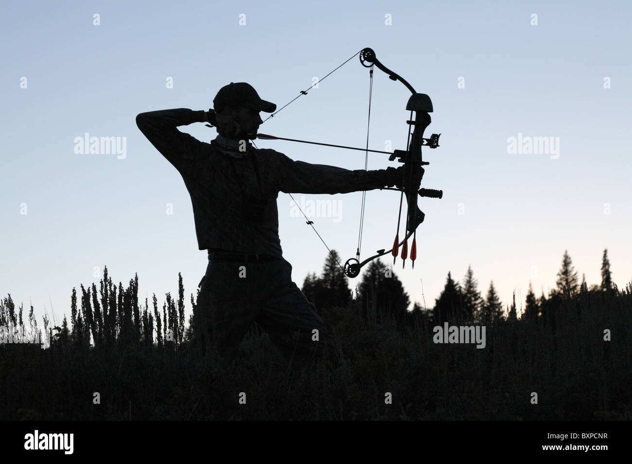 Silhouette des amerikanischen Bogen Jäger zeichnen Bogen zurück im Wald Stockfoto
