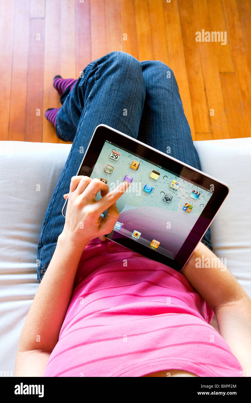 Frau entspannen Verwendung zu Hause eines Apple Mac iPad zu iTunes auf dem Schoß zu verwenden. Stockfoto
