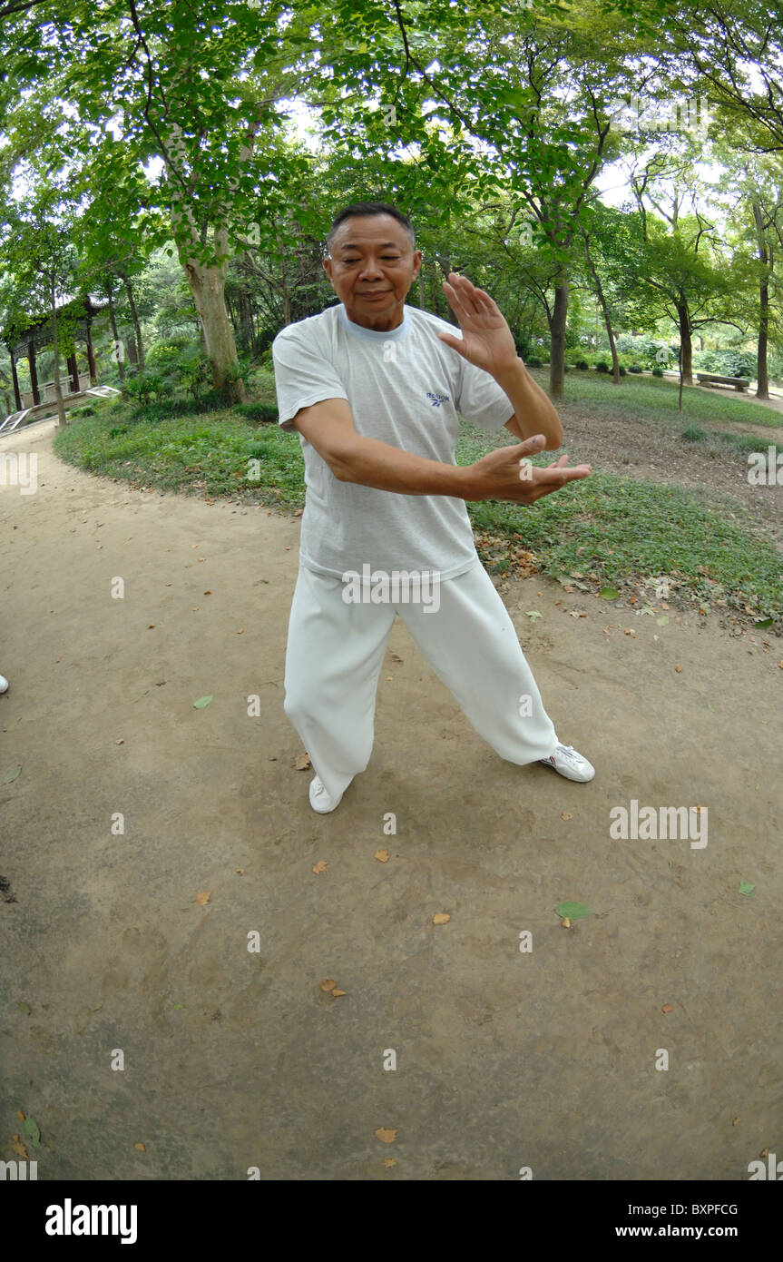 Ein Mann gekleidet in weißen Tai Chi Chuan Kampfkunst im Freien in schlanken West Lake Park Yangzhou Jiangsu Provinz in China zu tun Stockfoto