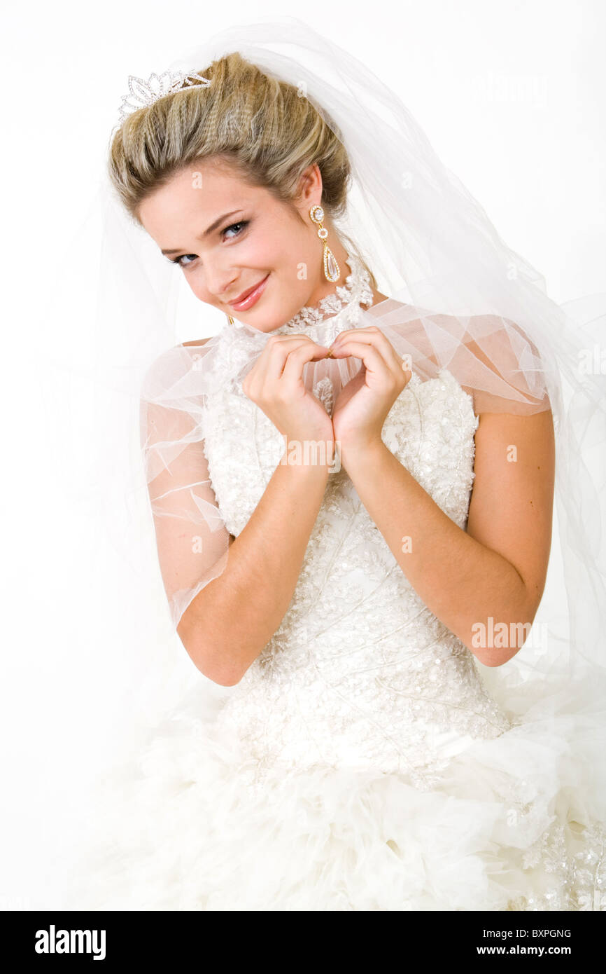 Porträt der Braut schneeweißes Kleid tragen und die Form des Herzens mit den Händen beim Blick in die Kamera Stockfoto