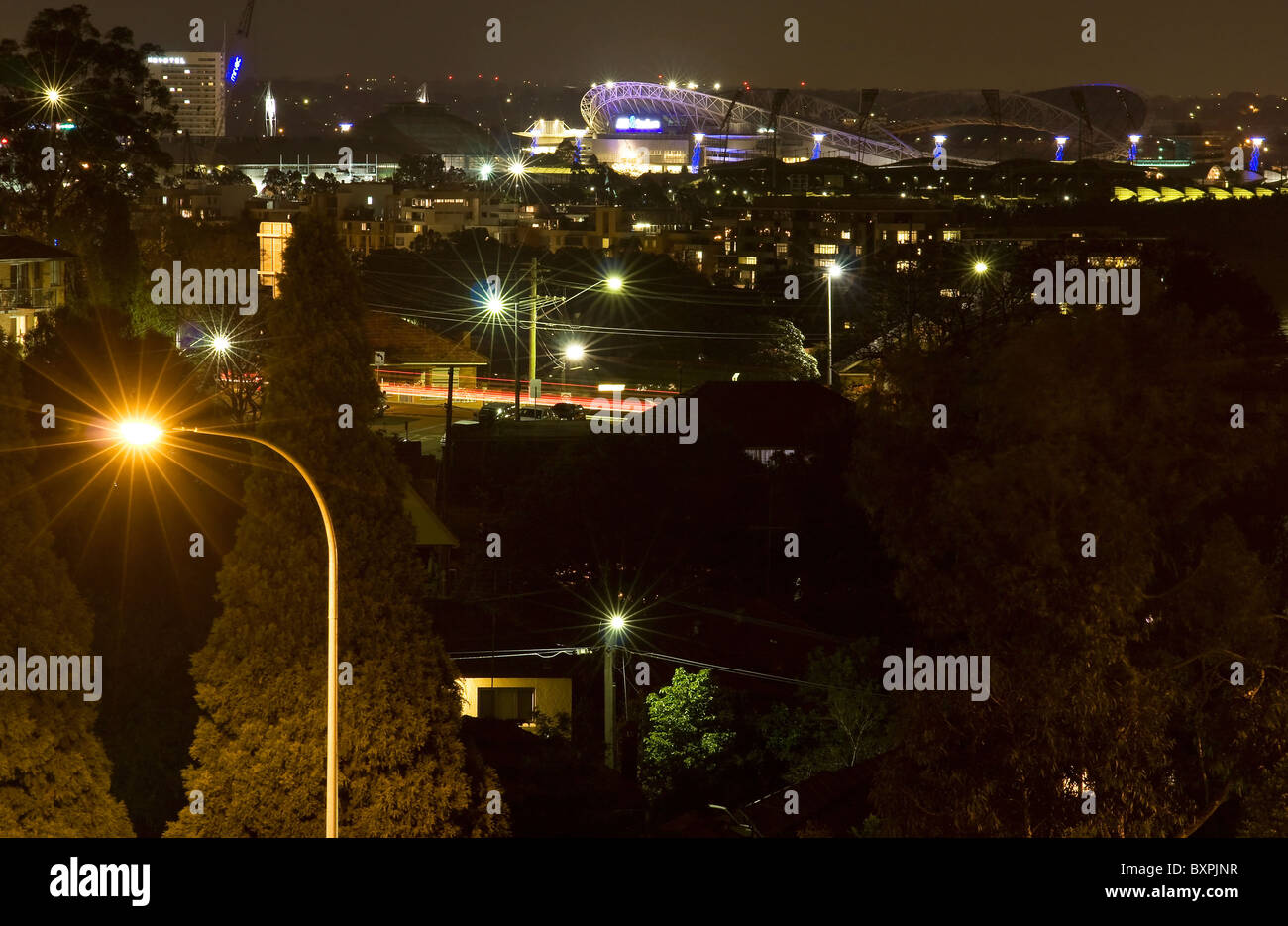 Eine urbane Nacht erleuchtet von Straßenlaternen in der Kulisse der Sydney Olympic Park. Stockfoto