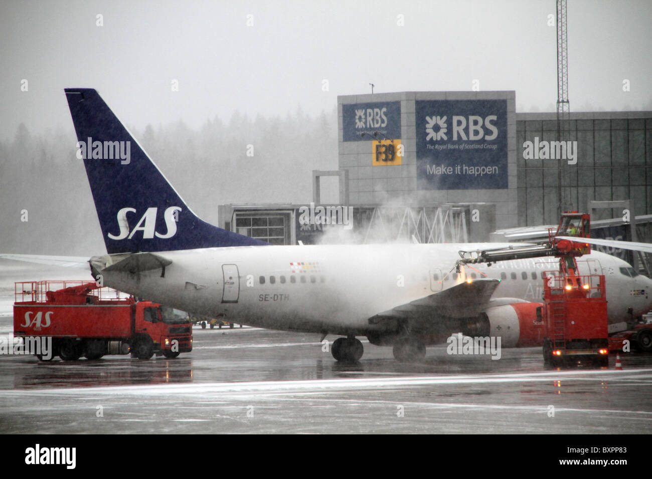 Flughafen Arlanda, Stockholm, Schweden. Eine SAS-Flugzeug ist auf dem Rollfeld an einem Schnee gebunden und nebligen Tag am Flughafen Arlanda enteist. Stockfoto
