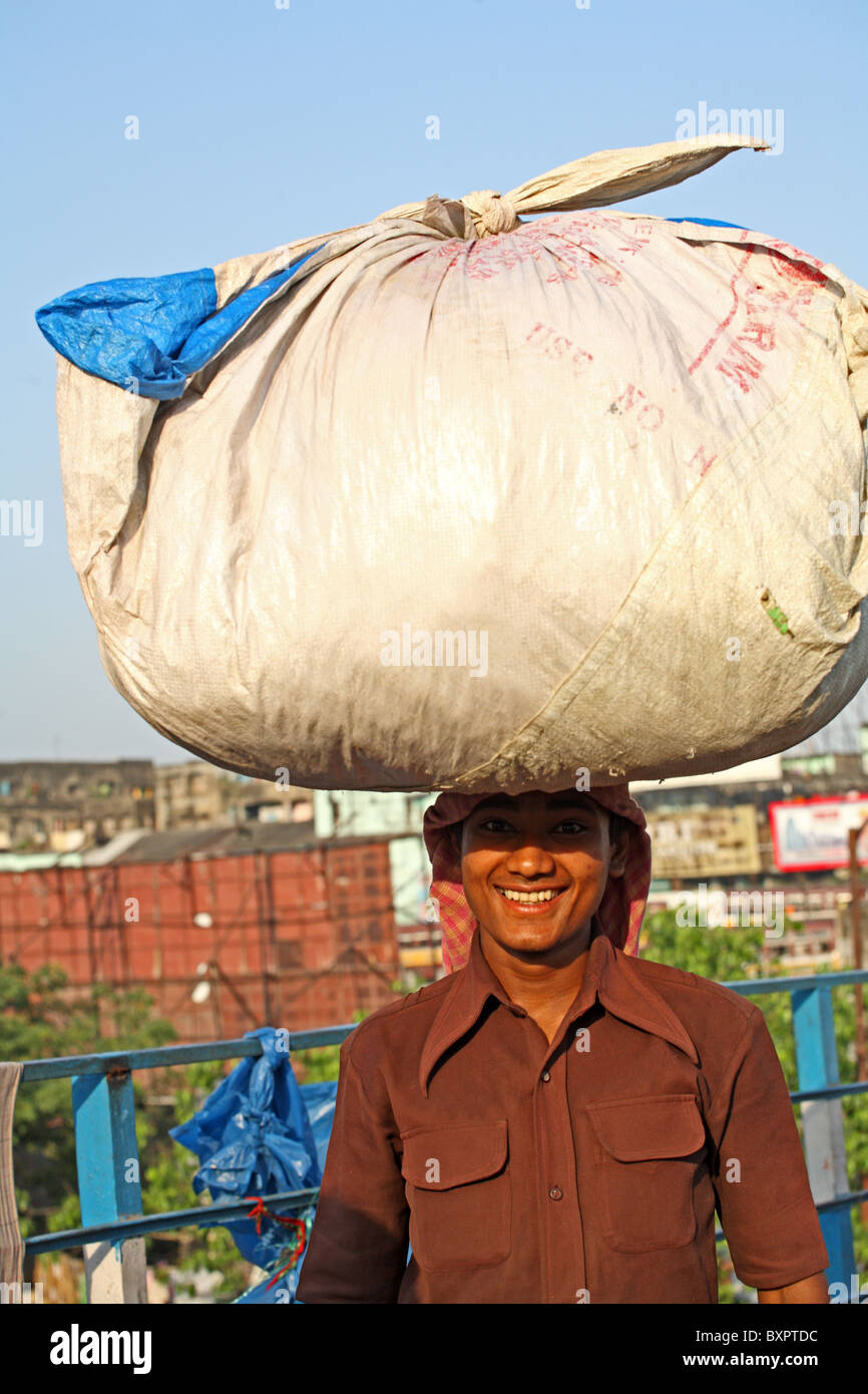 Lächelnd indischen Mann tragen Gewicht auf Kopf, Kalkutta Indien Stockfoto