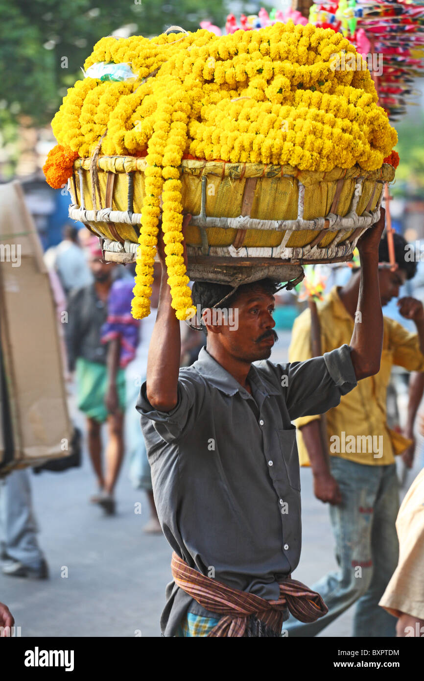 Mann mit Korb mit Girlanden auf Kopf in Kalkutta, Indien Stockfoto