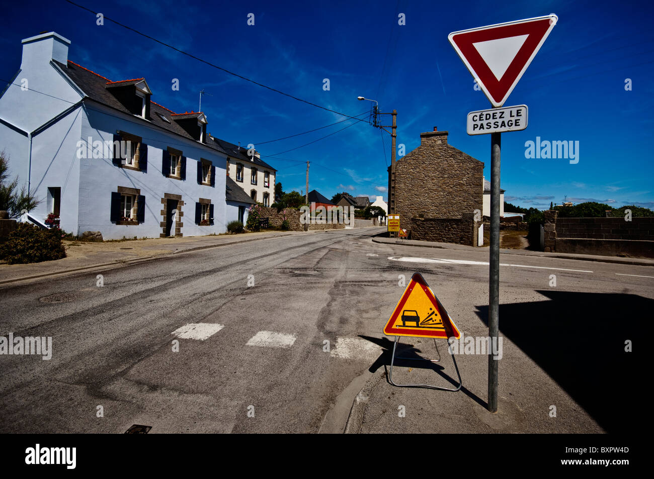 französisches Dorf Straße, viel Korn auf der Straße und ein Warnsignal für Getreide. Intensiven blauen Himmel, drei Weg überqueren Stockfoto