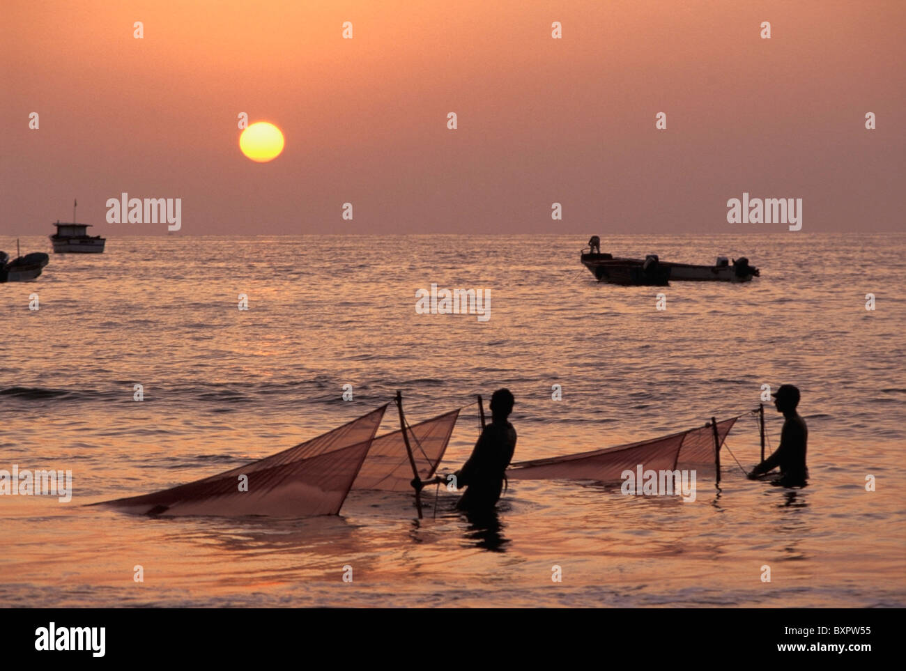 Fischer hält Netze im Meer bei Sonnenuntergang Stockfoto