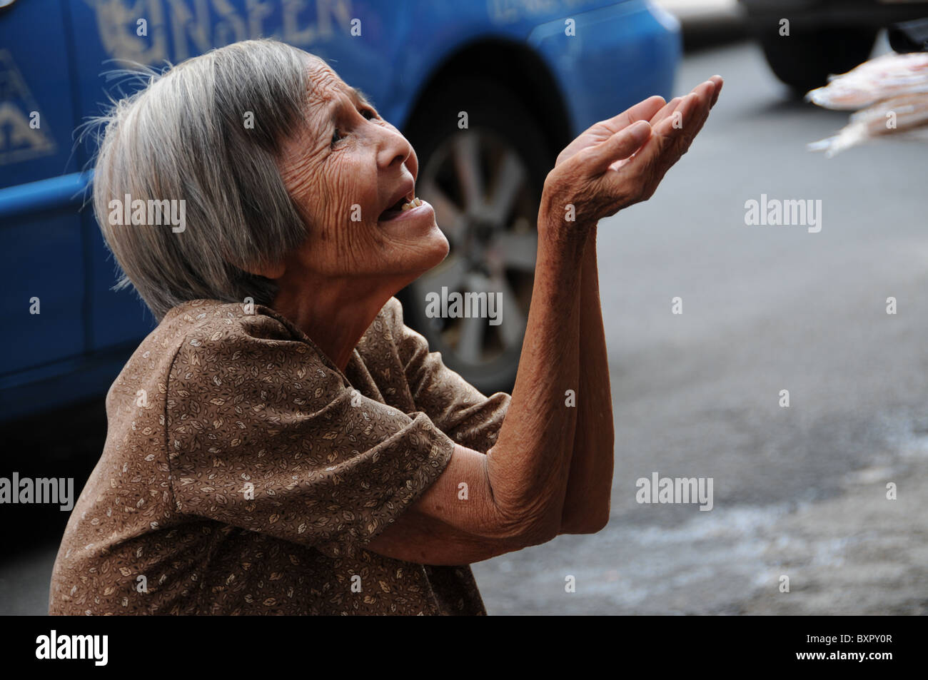 Alte asiatische Frau betteln um Geld Stockfoto