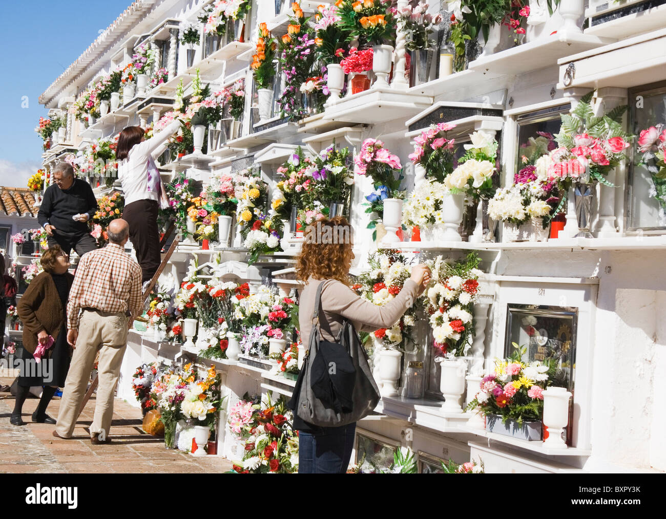 Menschen verlassen Blumen und Reinigung der Nischen ihrer lieben auf Allerheiligen auf dem örtlichen Friedhof. Stockfoto