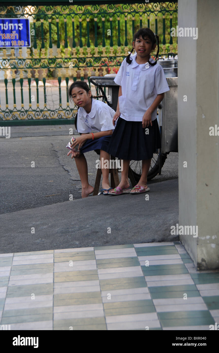 Zwei Schulmädchen warten nach der Schule auf eine Haus-Ecke Stockfoto