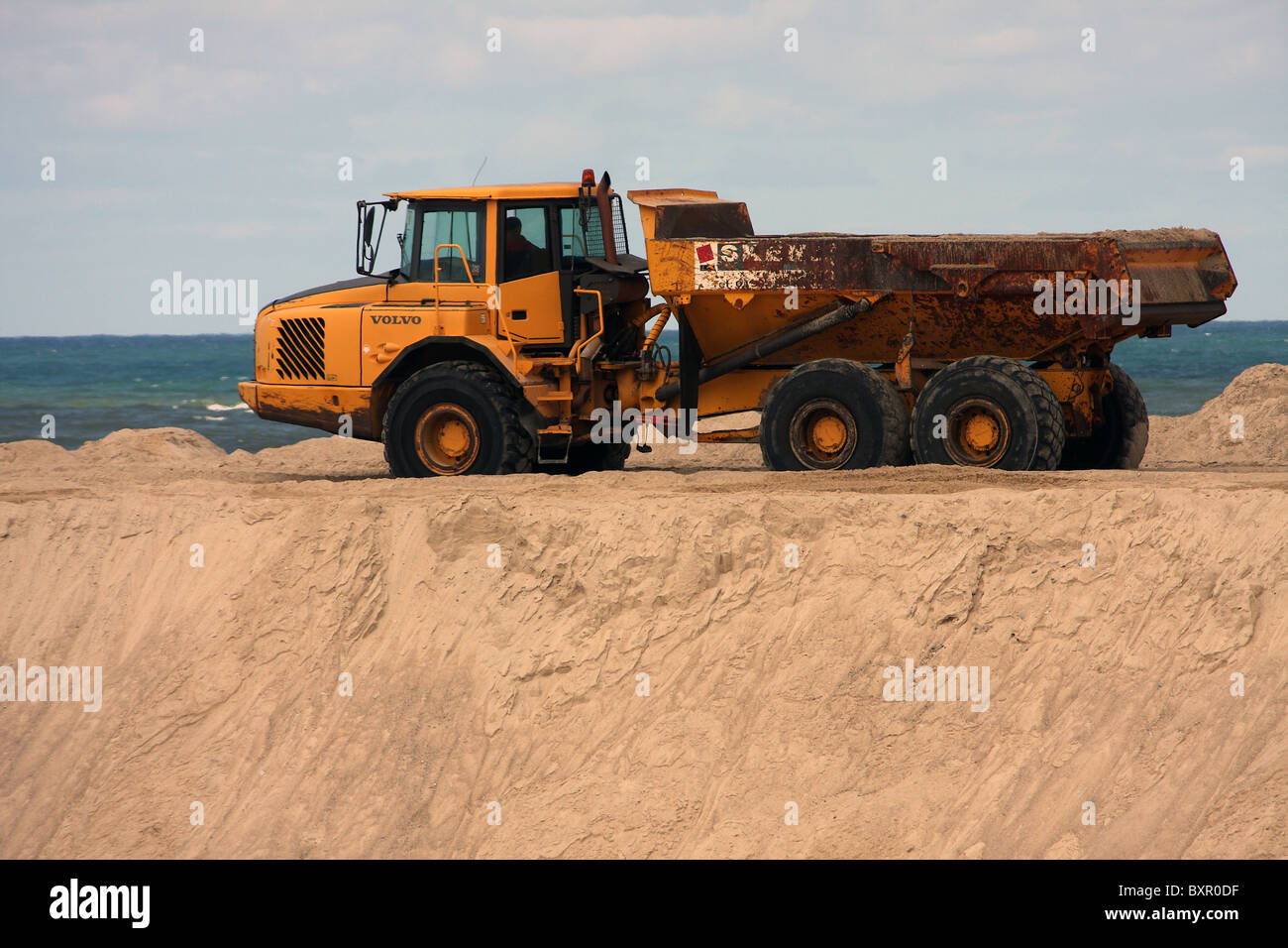 Ein Muldenkipper am Sandstrand am Meer bewegen Sand am Meer in Portugal Stockfoto