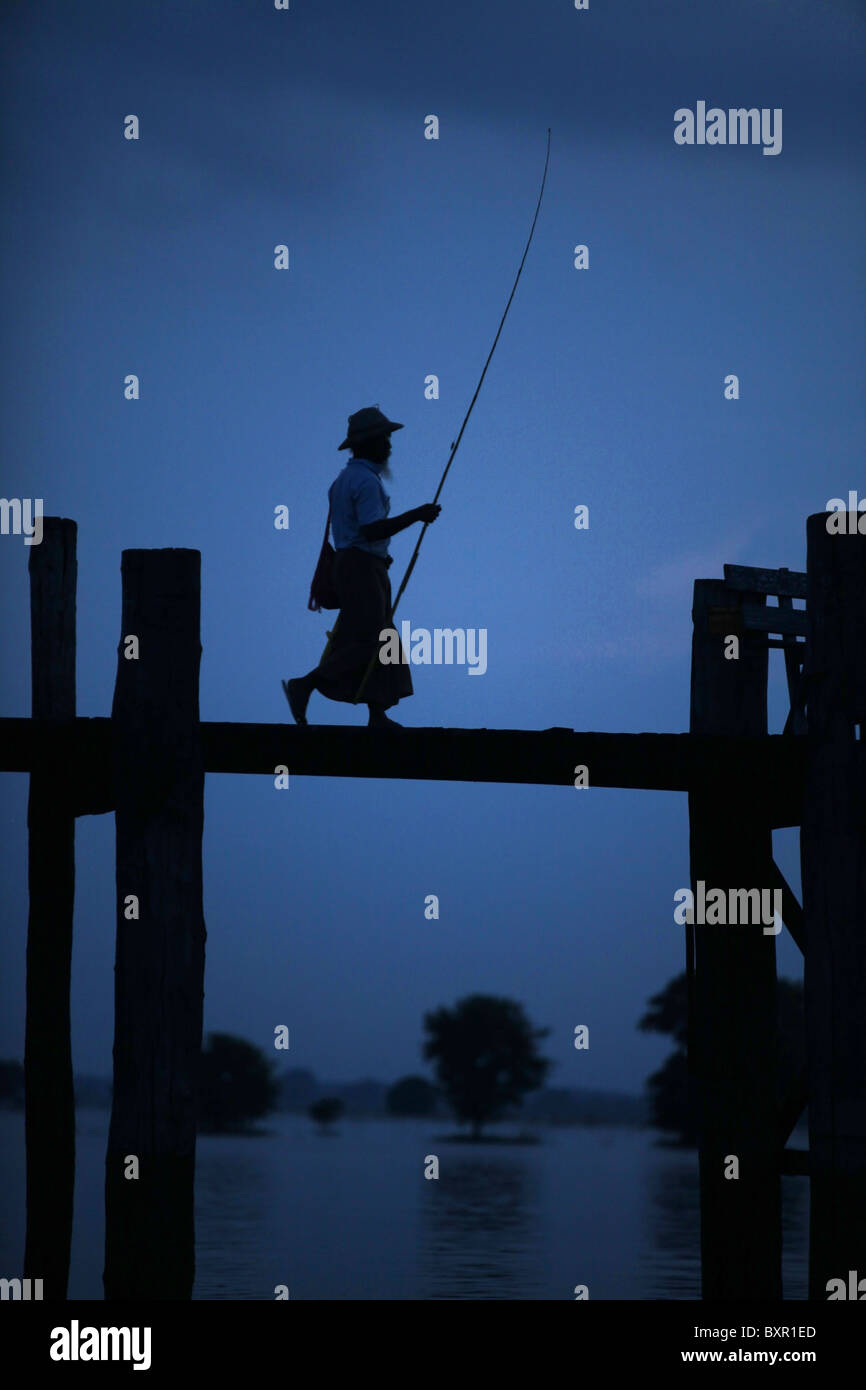 Ein einsamer Fischer der Teak U Bein Brücke, die Taugthaman See in Amarapura in der Nähe von Mandalay in Myanmar erstreckt. Stockfoto
