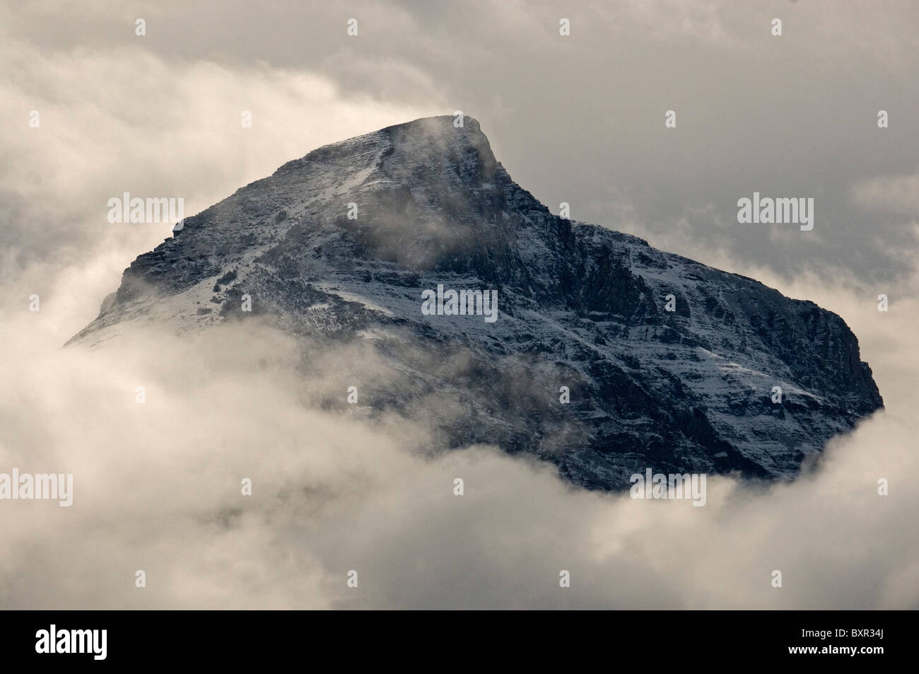 Schneebedeckte Berggipfel, die von Wolken eingehüllt Stockfoto