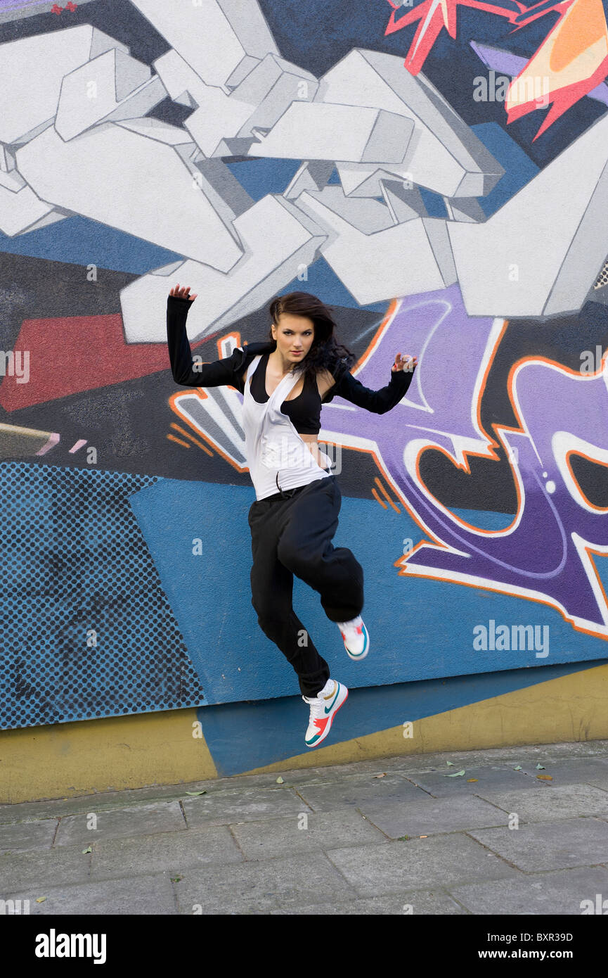 junge attraktive Frau im hip Hop Kleid tanzen und springen im städtischen Hintergrund Stockfoto