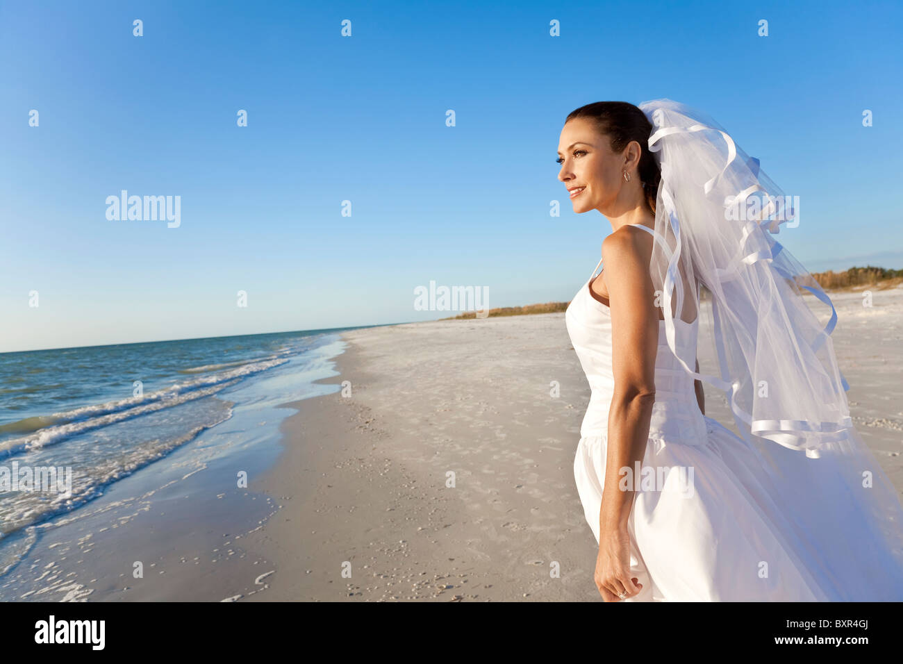 Eine verheiratete Frau Braut in ihrem Hochzeitskleid in der Sonne an einem wunderschönen tropischen Strand Stockfoto