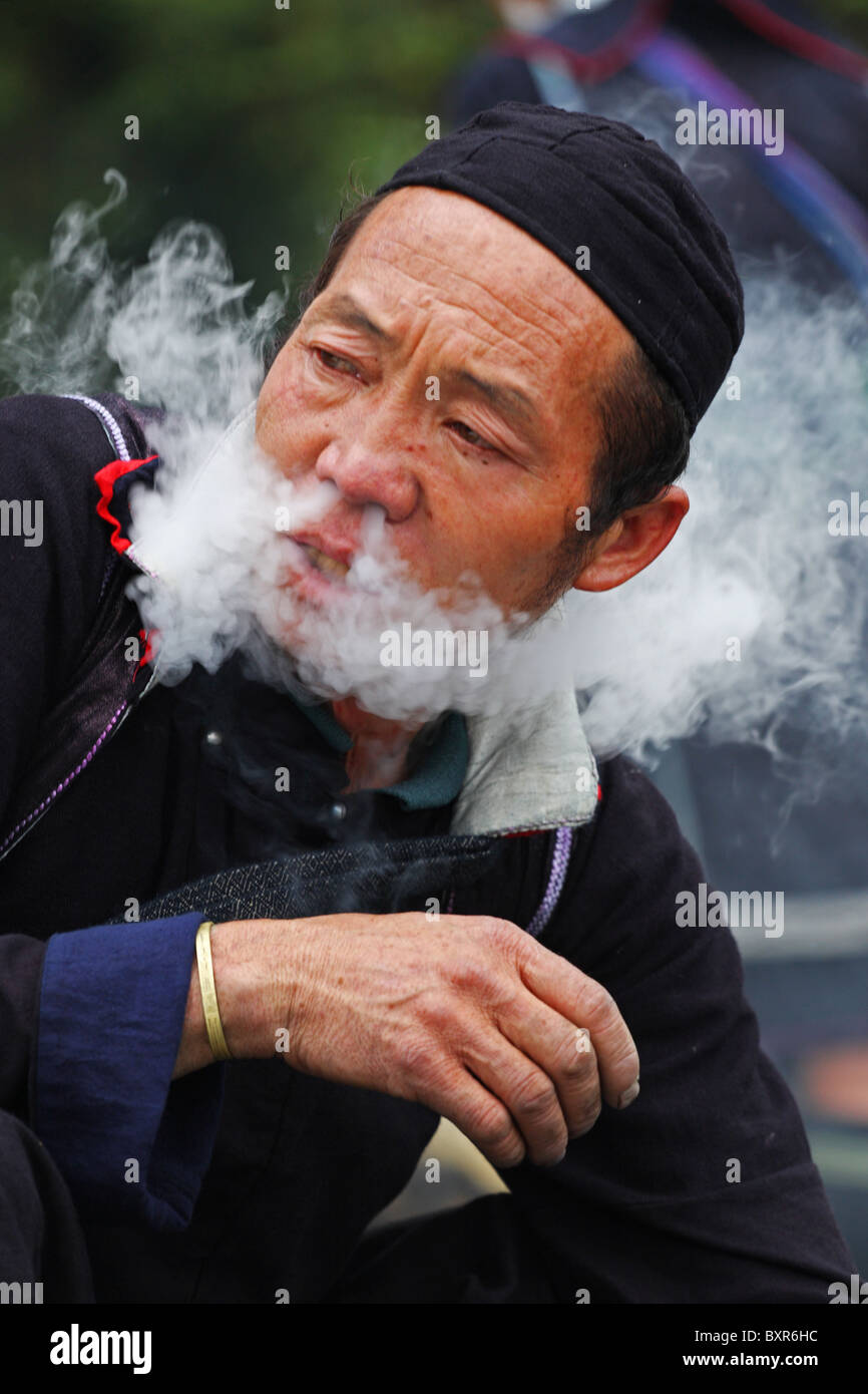 Black Hmong männlich Einblasen von Tabakrauch durch Nasenlöcher, Sapa, Nord-Vietnam Stockfoto