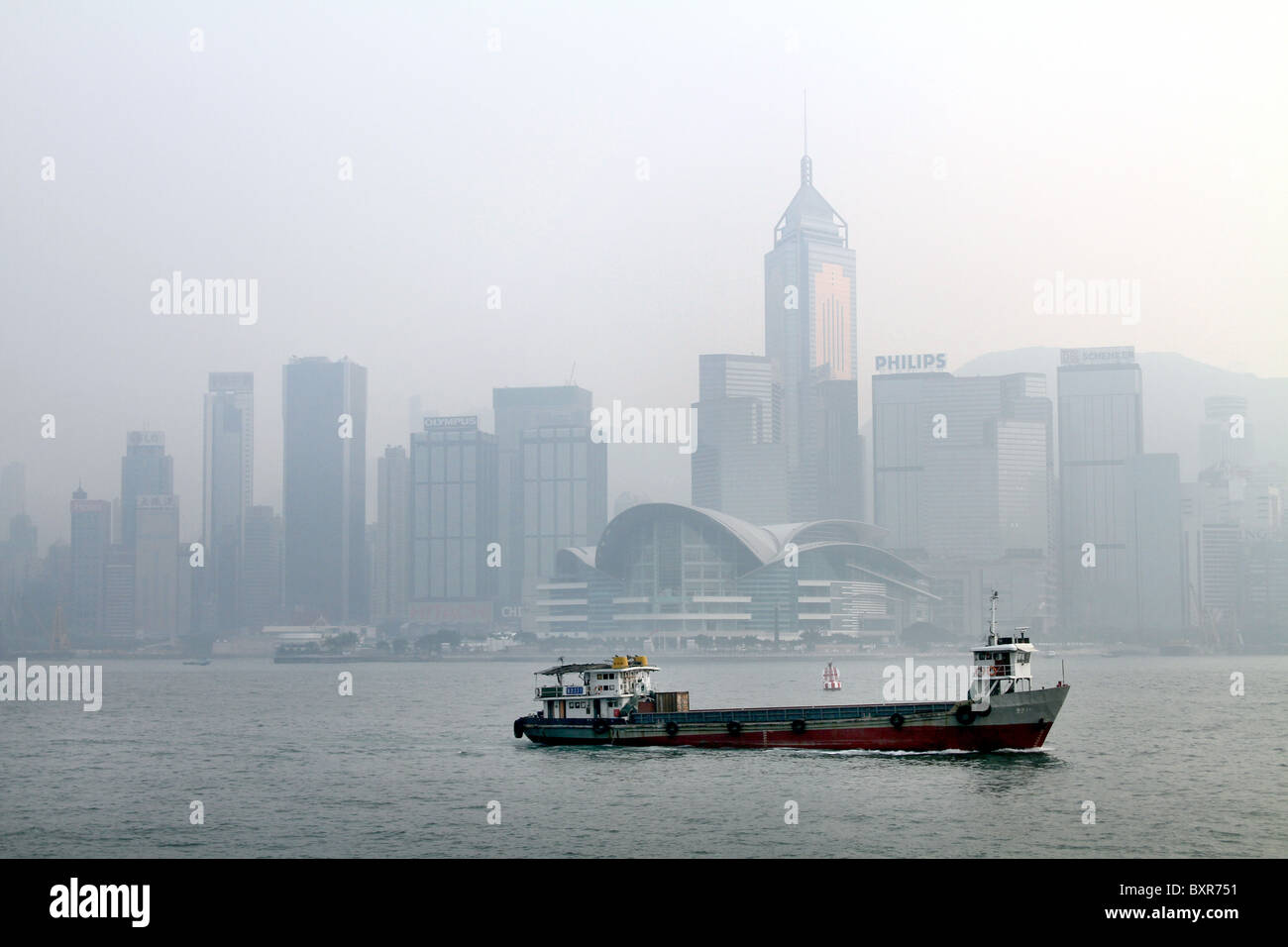 Boot im Hafen von Hongkong gegen die Skyline in Hong Kong, China Stockfoto