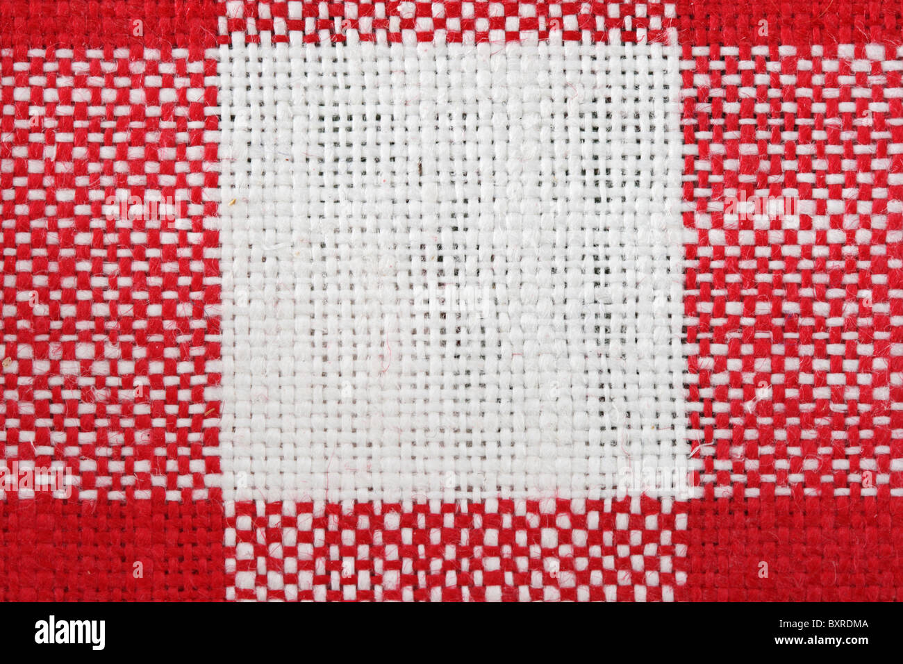 rote und weiße Tischdecke Makro mit einem einzigen weißen Quadrat und die umliegenden roten Bereiche Stockfoto