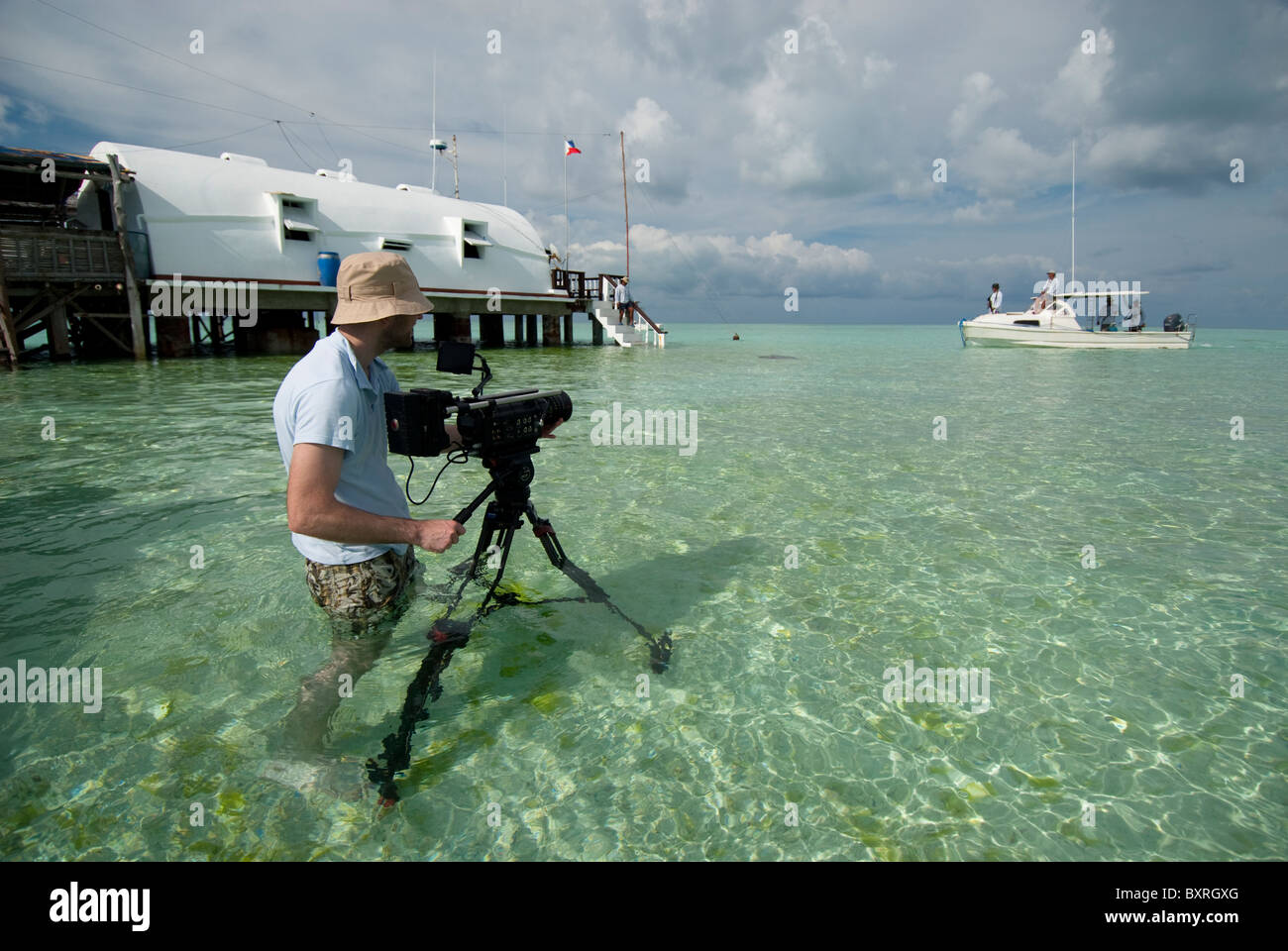 Mann filmt in Wasser flach genug stehen, Tubbataha, Palawan, Philippinen Stockfoto