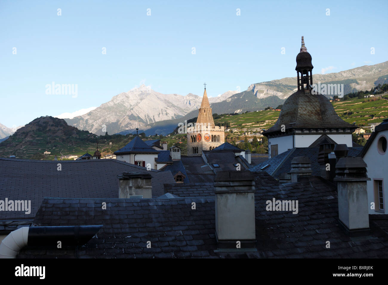 Sonne scheint eine Kirche andere Dächer in der alten Stadt Sion, Wallis, Schweiz überragt Stockfoto