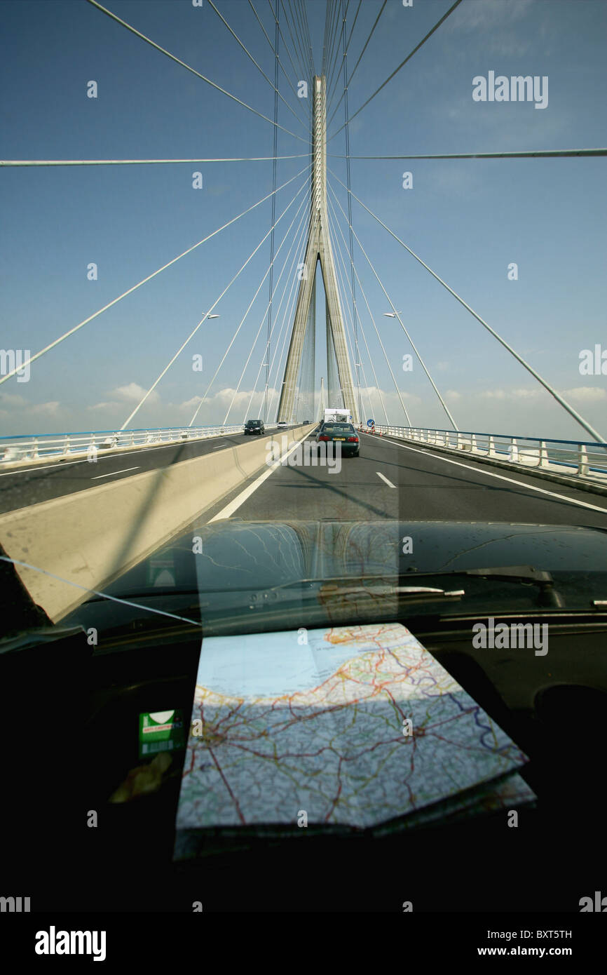 Ein Auto über eine moderne Brücke mit einer französischen Karte auf dem Armaturenbrett Stockfoto