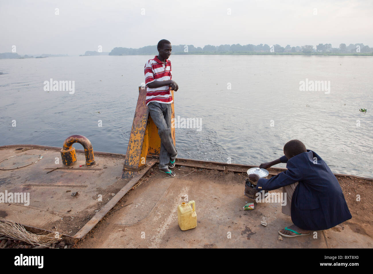 Juba-Port: große Fluss Lastkähne auf der Anklagebank gebunden sind. Ein junge Köche Frühstück auf dem Lastkahn-Deck. Stockfoto