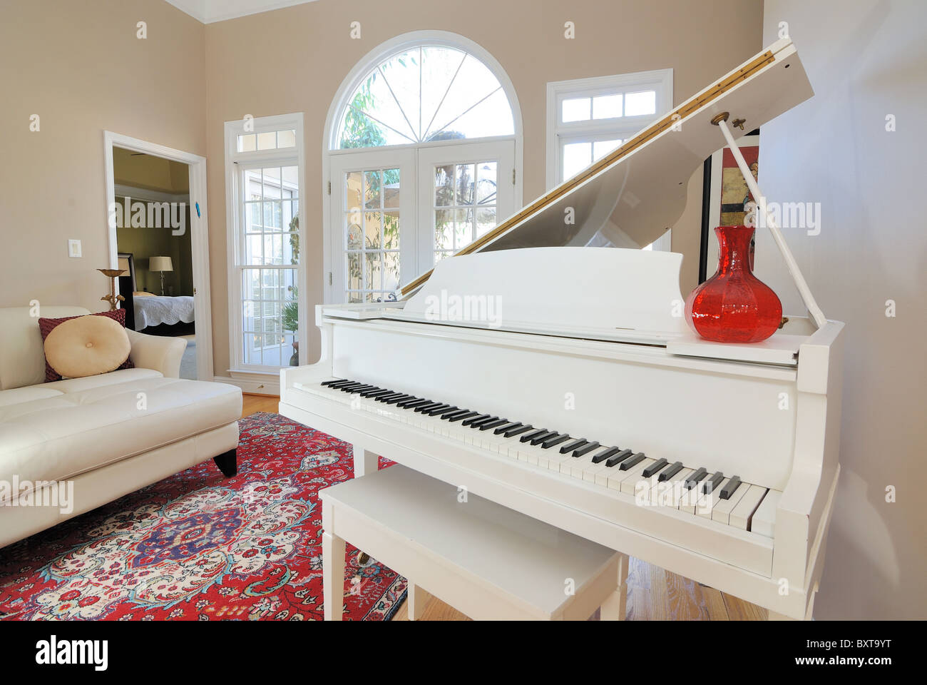 Zeitgenössische Wohnzimmer Einrichtung mit Sofa, Couch, Klavier und Fenster Blick auf die Terrasse Deck. Stockfoto