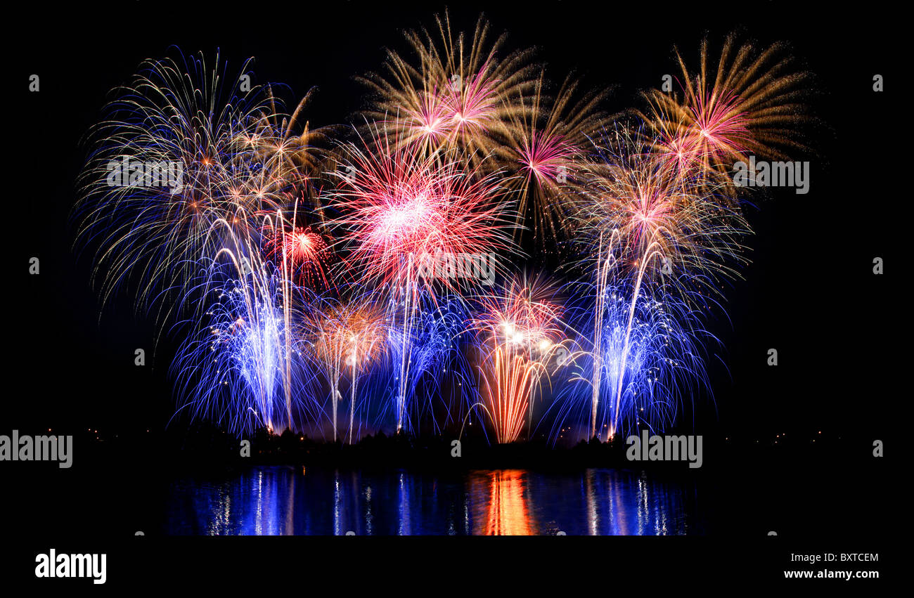 Eine Nachtzeit sich bunte Antenne Feuerwerk im Wasser wider. Stockfoto