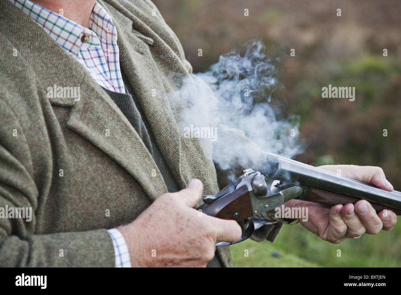 Detail-Foto von gut gekleideten Mann, der eine Schrotflinte während eines Shootings Fasan hält. Stockfoto