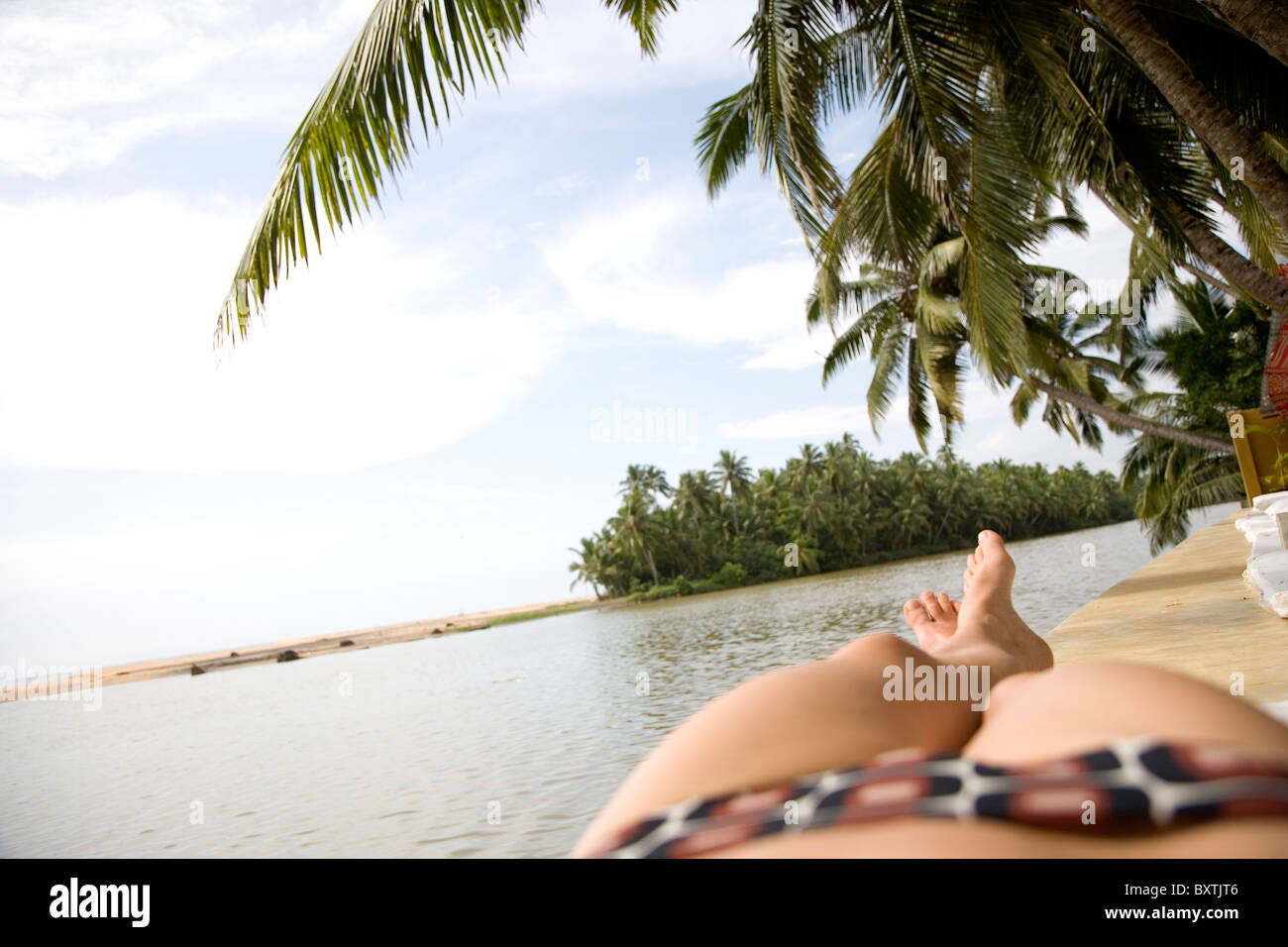 Frau In gemusterten Bikini Sonnenbaden vom Ozean Stockfoto