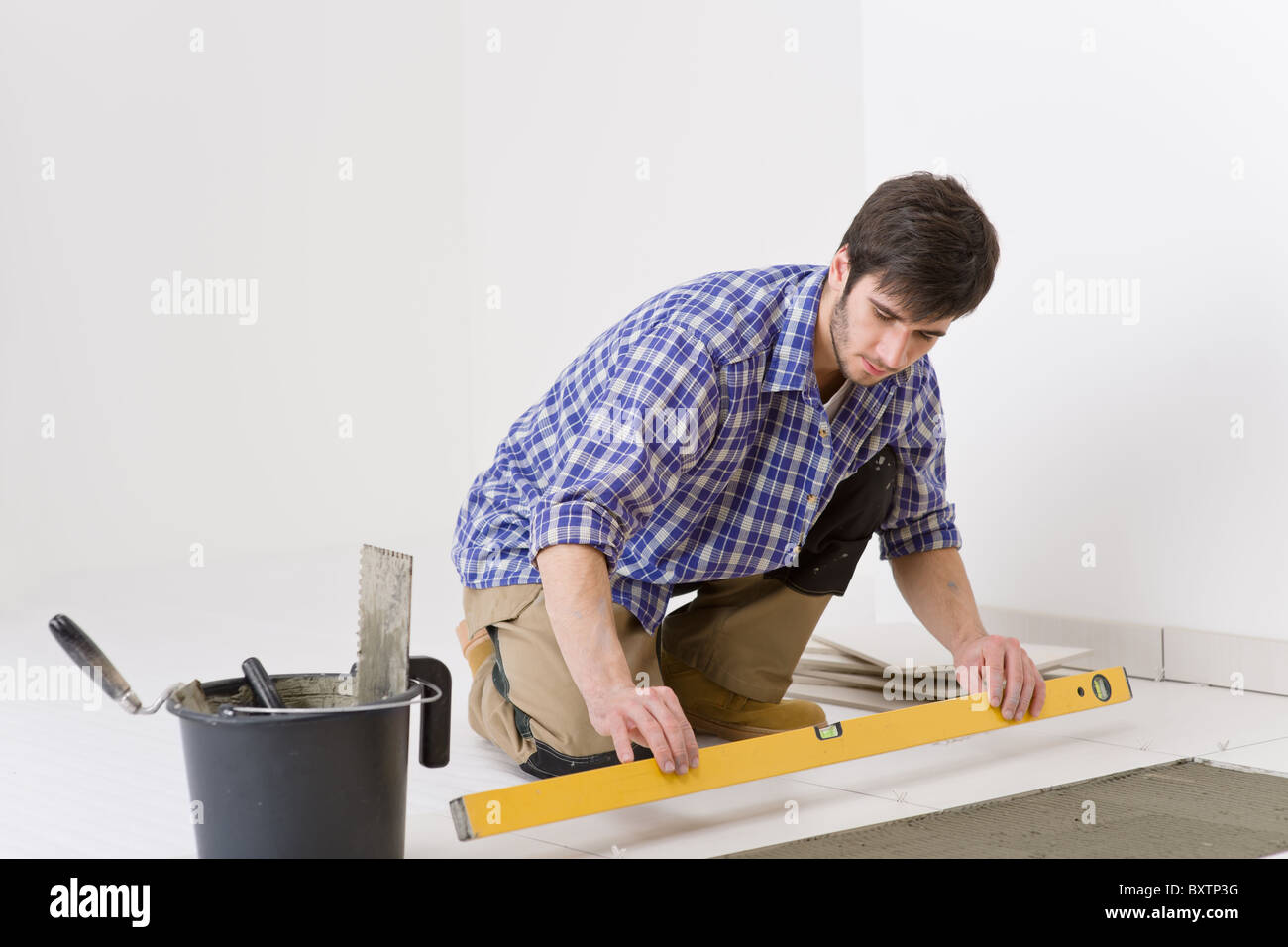 Home Fliesen Verbesserung - Handwerker mit Ebene Festlegung Fliesenboden Stockfoto